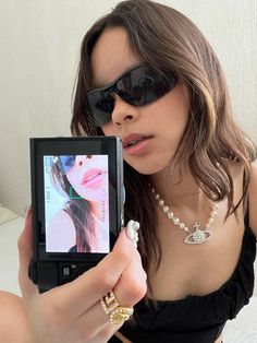 a woman taking a selfie with her cell phone and pearls on the necklaces