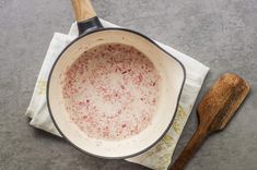 a wooden spoon sitting on top of a cloth next to a pan filled with food