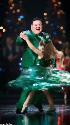 a man and woman dancing on stage with lights in the background