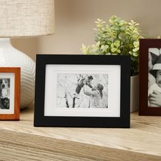 two framed photos sitting on top of a wooden table next to a vase with flowers