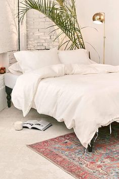 a bed with white linens and pillows in a bedroom next to a rug on the floor