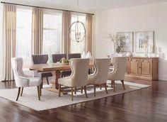 the dining room table is surrounded by beige chairs and white upholstered arm chairs