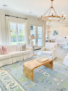 a living room filled with furniture and a chandelier hanging from the ceiling over a blue rug