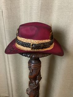 This is a custom weathered hat with incredible detail.  Burgandy felt hat with band of tan fabric with Burgandy flowers. Leather hat band.  Gorgeous broach in front.  Chain ant bottom.  Hat has been wood burned a beautiful scroll design.   Authentic Turkey feathers in back.   Adjustable band inside to fit any size. Rustic Adjustable Felt Hat For Kentucky Derby, Rustic Festival Hat Bands For Short Brim Hats, Rustic Style Hat Bands For Kentucky Derby, Rustic Brimmed Hat Band For Kentucky Derby, Vintage Felt Hat For Country Events In Fall, Rustic Short Brim Fedora For Kentucky Derby, Handmade Vintage Felt Hat For Country Events, Bohemian Adjustable Felt Hat, Vintage Handmade Hat Band For Western-themed Events