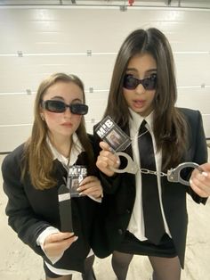 two women in suits and ties holding up some kind of pair of handcuffs that are attached to each other