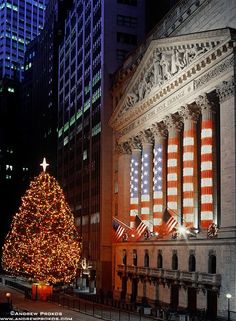 a large christmas tree is lit up in front of the new york stock exchange at night