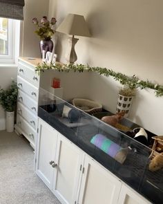 a kitchen with white cabinets and black counter tops next to a window in the corner