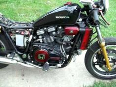 a black motorcycle parked on top of a cement slab in the grass next to a sidewalk