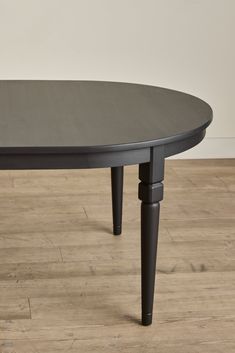 an oval table with black legs on a wooden floor