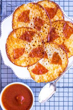 a pizza on a plate with sauce next to it and a bowl of dipping sauce