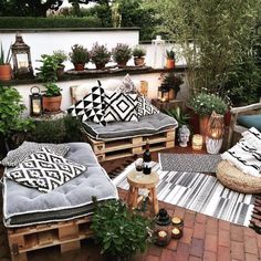 an outdoor patio with lots of plants and pillows on the couches next to it