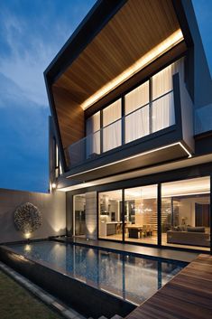 a modern house with a pool in the middle of it at night, lit up by lights