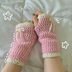 a pair of pink crocheted mittens laying on top of a bed