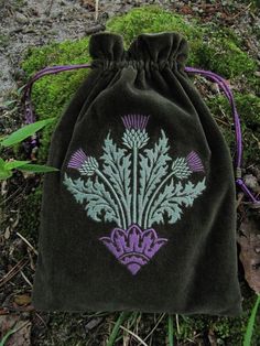 a drawstring bag sitting on the ground next to some grass and plants in it