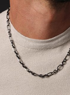 Oxidized Sterling and Titanium Coated Figaro Inspired Cable Chain Necklace This chain is first coated with black titanium and then parts of it are polished off to create the black/silver contrast look exposing some of the sterling silver underneath the titanium. Chain: 925 Sterling Silver with partial Titanium Coating Width: 7mm Link length: 12mm (long link) Lobster claw clasp Kyle is wearing the 20 inch chain. Kyle's neck is 15 1/2 inches. Made in the USA. Gunmetal Box Chain Link Necklace, Gunmetal Stainless Steel Necklace With Oxidized Finish, Gunmetal Oxidized Stainless Steel Necklace, Modern Gunmetal Link Jewelry, Black Sterling Silver Link Chain Necklace, Modern Gunmetal Jewelry With Oxidized Finish, Black Figaro Chain Necklace, Black Sterling Silver Link Necklace, Black Figaro Chain Link Necklace