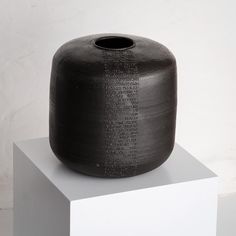 a black vase sitting on top of a white block