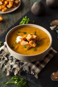 a bowl of soup with bread and sour cream on the side next to other food