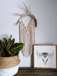 a potted plant sitting on top of a wooden table next to a wall hanging