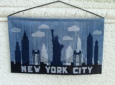 a new york city banner hanging on a wall with the statue of liberty in the background