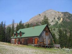 an old log cabin in the mountains surrounded by pine trees