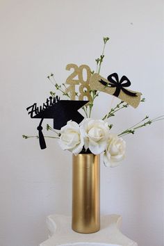 a gold vase filled with white flowers on top of a table