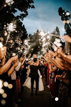 a bride and groom are surrounded by sparklers as they walk down the aisle at their wedding