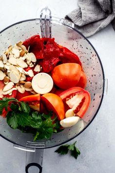 tomatoes, almonds and parsley in a blender on a white counter top