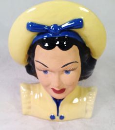 a ceramic figurine of a woman wearing a yellow hat and blue bow tie