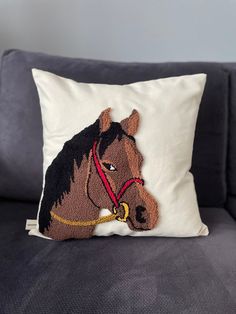 a pillow with a horse head on it sitting on a couch next to a wall