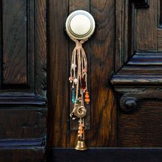 a door handle with beads hanging from it's side and a bell on the front