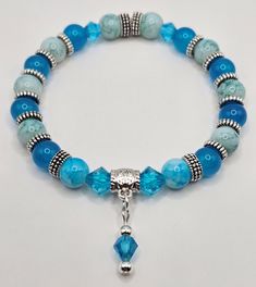 Imagine standing on the shores of a tranquil lagoon, where the waters shimmer in mesmerizing shades of turquoise under the silver moonlight. This bracelet captures the serene beauty of such a scene, blending together beads of captivating turquoise and delicate glass crystals, accented with gleaming silver details. Each bead is a reflection of the lagoon's tranquility, evoking the soothing embrace of calm waters and the celestial glow of a moonlit night. Adorning this bracelet is a tiny charm centerpiece, a symbol of wanderlust and adventure. Its intricate design adds an extra touch of elegance to the ensemble. Wearing this bracelet is like carrying a piece of paradise with you wherever you go. It's a celebration of freedom and exploration, inviting you to embrace the wonders of the world. Turquoise Aquamarine Beaded Bracelets With Natural Stones, Turquoise Aquamarine Beaded Bracelets With Gemstone Beads, Spiritual Turquoise Beaded Bracelets With Czech Glass, Turquoise Aquamarine Gemstone Beaded Bracelets, Adjustable Beaded Aquamarine Bracelets, Turquoise Aquamarine Beaded Bracelets As Gift, Spiritual Turquoise Czech Glass Bracelets, Spiritual Turquoise Czech Glass Bracelet, Beaded Aquamarine Bracelets