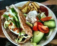 a white plate topped with a cut in half sandwich next to french fries and veggies