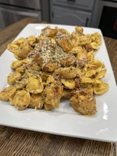 a white plate topped with pasta covered in sauce and cheese on top of a wooden table