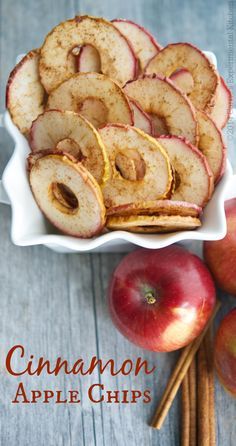 cinnamon apple chips in a white bowl next to apples and cinnamon sticks