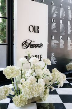 white flowers are sitting in a vase on a black and white checkerboard table