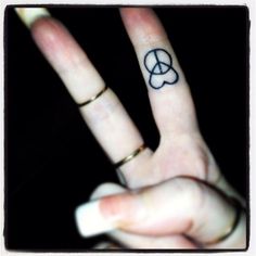 a person with a peace sign tattoo on their finger