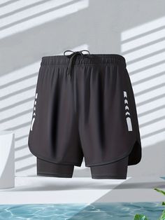 a pair of black shorts sitting on top of a white wall next to a pool