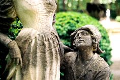 a statue of a woman with her hands on her head next to a stone angel