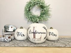 three white pumpkins sitting on top of a table next to a wreath and other decorations