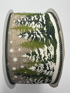 a spool of green and white ribbon with trees on it