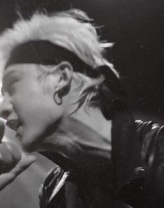 a black and white photo of a woman singing into a microphone with her hair pulled back