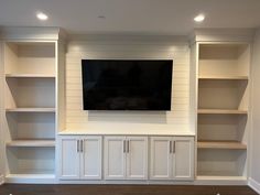 a flat screen tv mounted to the side of a white bookcase in a living room