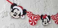 mickey and minnie mouse christmas decorations hanging on the wall with candy canes in front of them