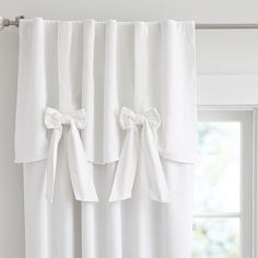 white curtains with bows hanging on them in front of a window