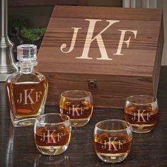 four personalized whiskey glasses in front of a wooden box with the initials j k f