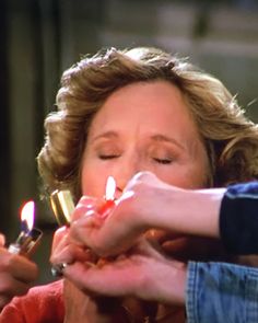 two women lighting candles in their hands while another woman holds the other hand out to her