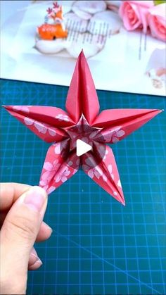 someone is holding up a red origami star