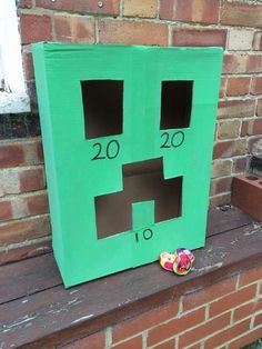 a green cardboard box with two faces cut out