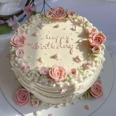 a birthday cake decorated with pink roses on a table