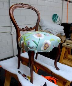 a chair that is covered in snow and has flowers on the upholstered seat